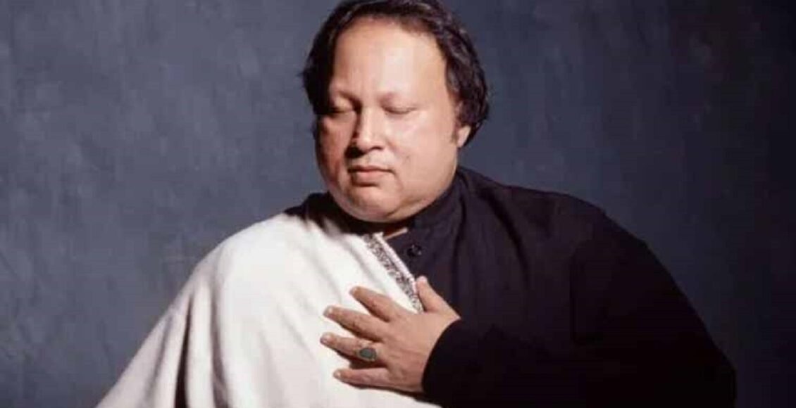 استاد نصرت فتح علی خان — قوالی کے شہنشاہ، مائیک کے سامنے مسکراتے ہوئے، پس منظر میں روح پرور روشنی، دنیائے موسیقی کا عظیم ترین فنکار۔